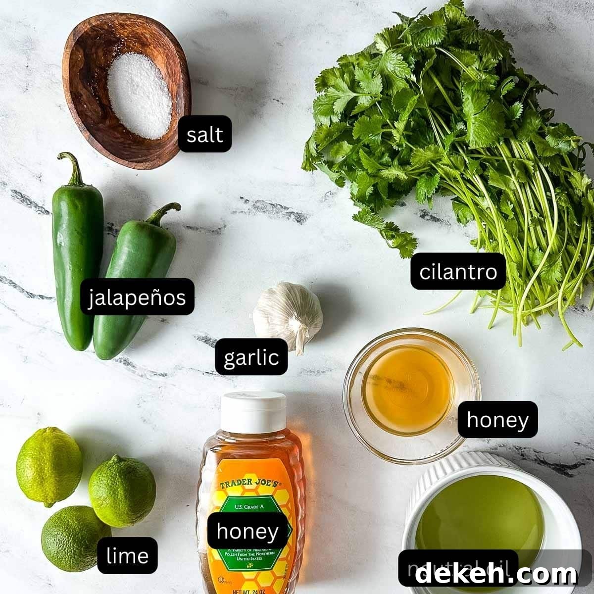 The labeled ingredients for honey jalapeno lime vinaigrette sit on a white marble counter.