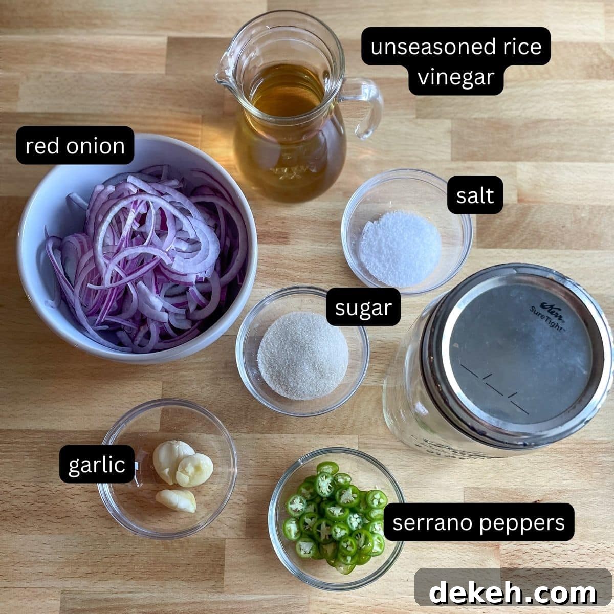 Labeled ingredients for spicy pickled onions sit on a wooden cutting board.