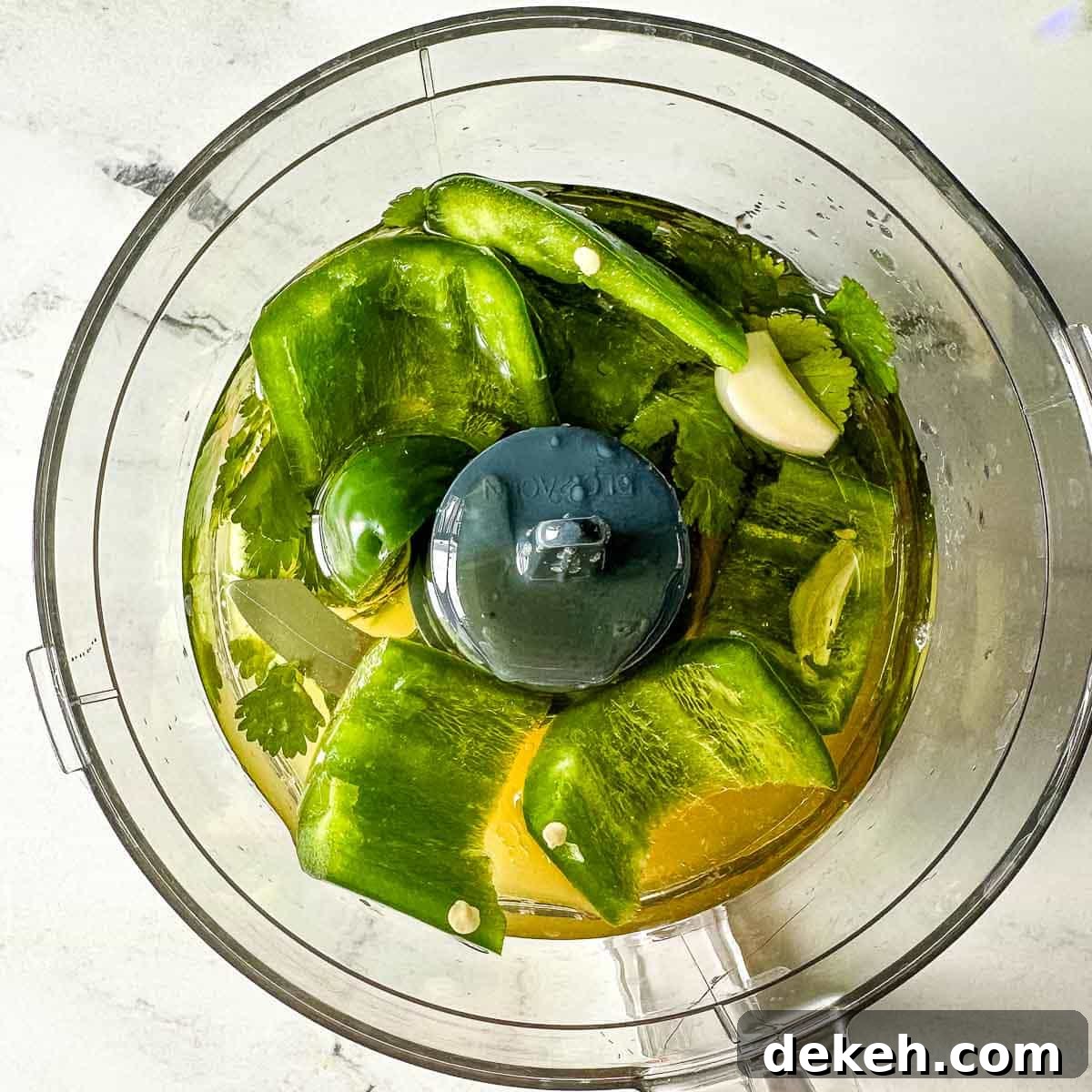 The ingredients for honey lime jalapeno vinaigrette are shown in a mini food processor.