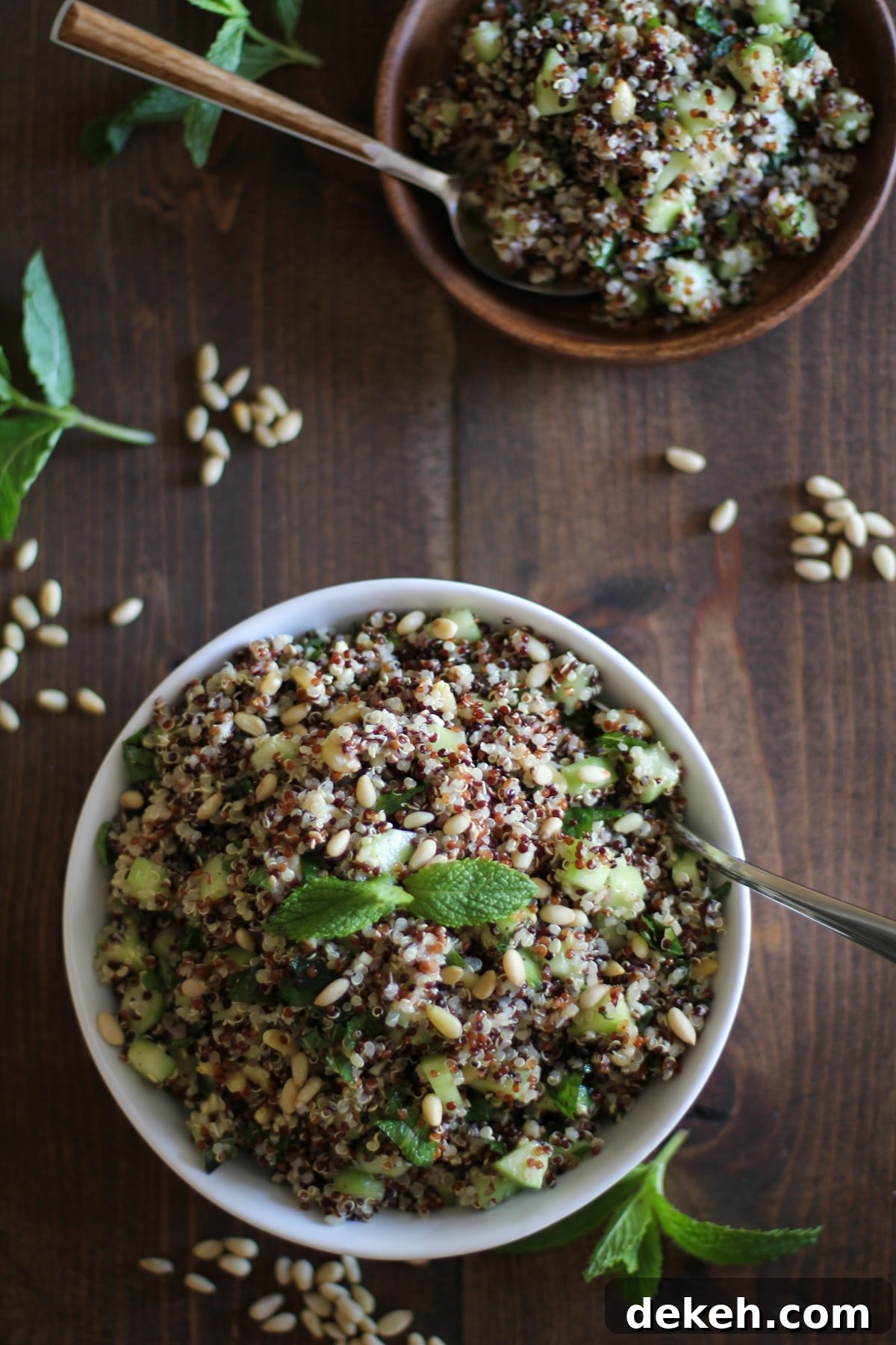 Big white bowl of quinoa salad with cucumber, pine nuts and mint lime dressing.