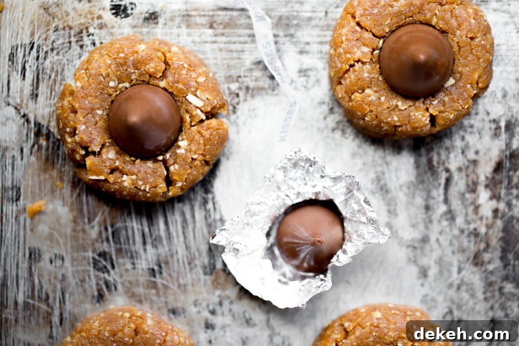 overhead photo of no bake peanut butter hershey's kiss cookies on sheet pan next to hershey's kiss in wrapper