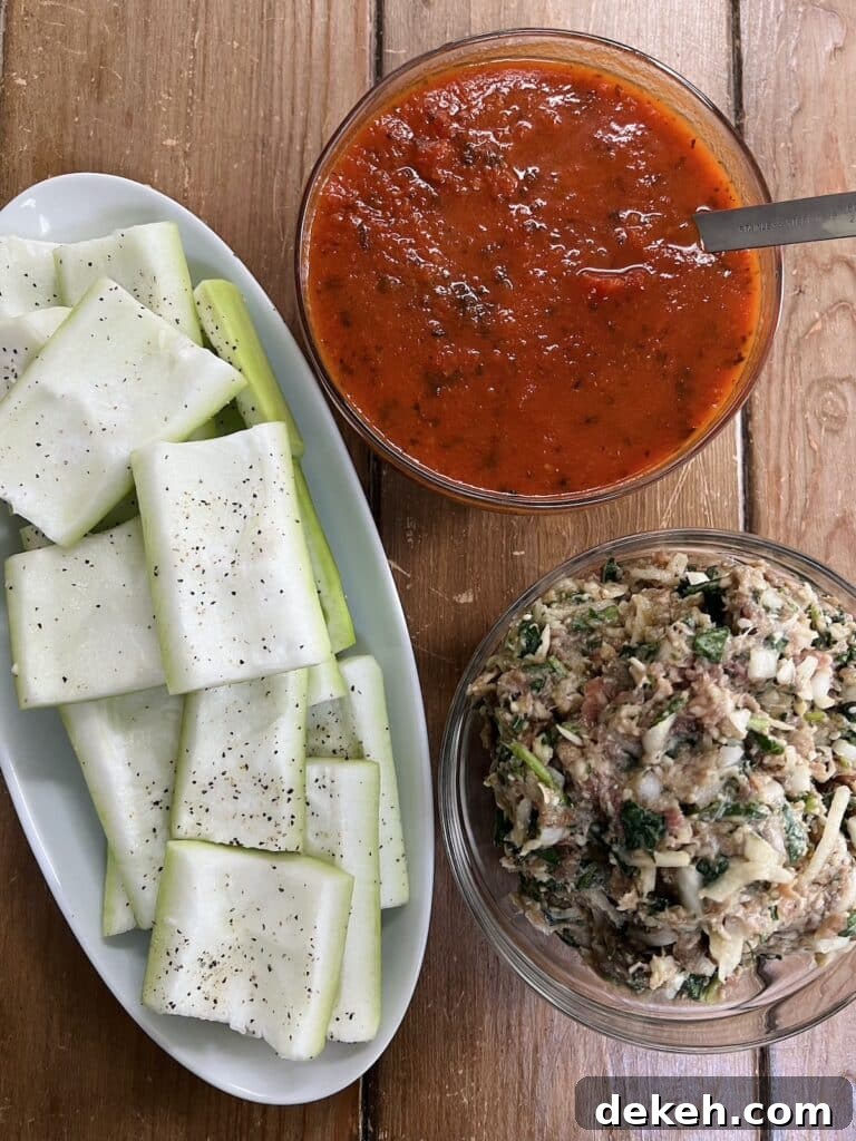 Prepped and seasoned squash ready to stuff on a white platter next to glass bowls with tomato sauce and filling, respectively.