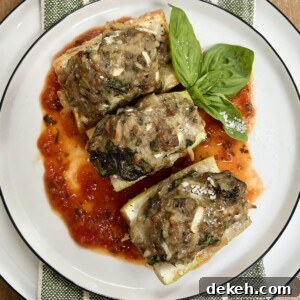 Three pieces of Baked Stuffed Cucuzza Squash over tomato sauce on white plate with basil sprig garnish.