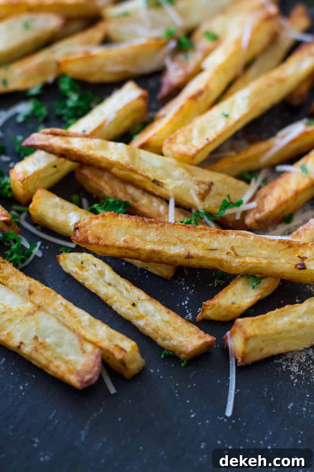 Close up of air fried french fries topped with seasoning salt, Parmesan cheese and parsley.