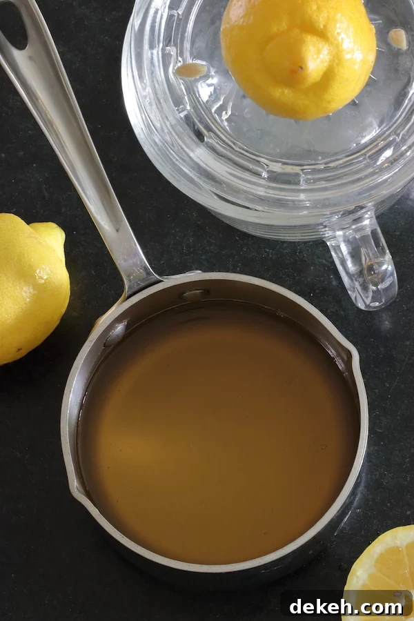 A small saucepan of simple syrup surrounded by lemons
