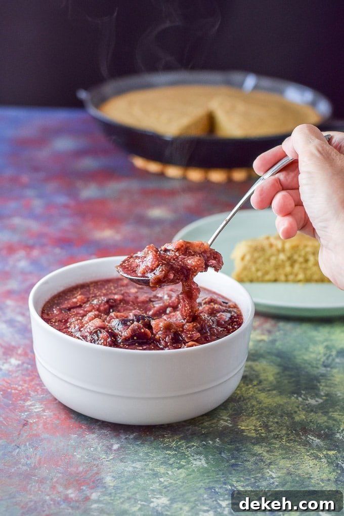 A spoonful of the fig sauce held over a white bowl with some cornbread in the background
