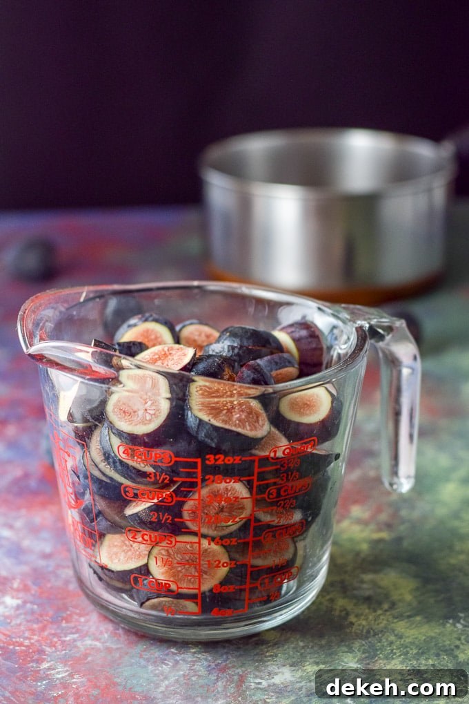 Cut up figs in a glass measuring cup with a pan in the background