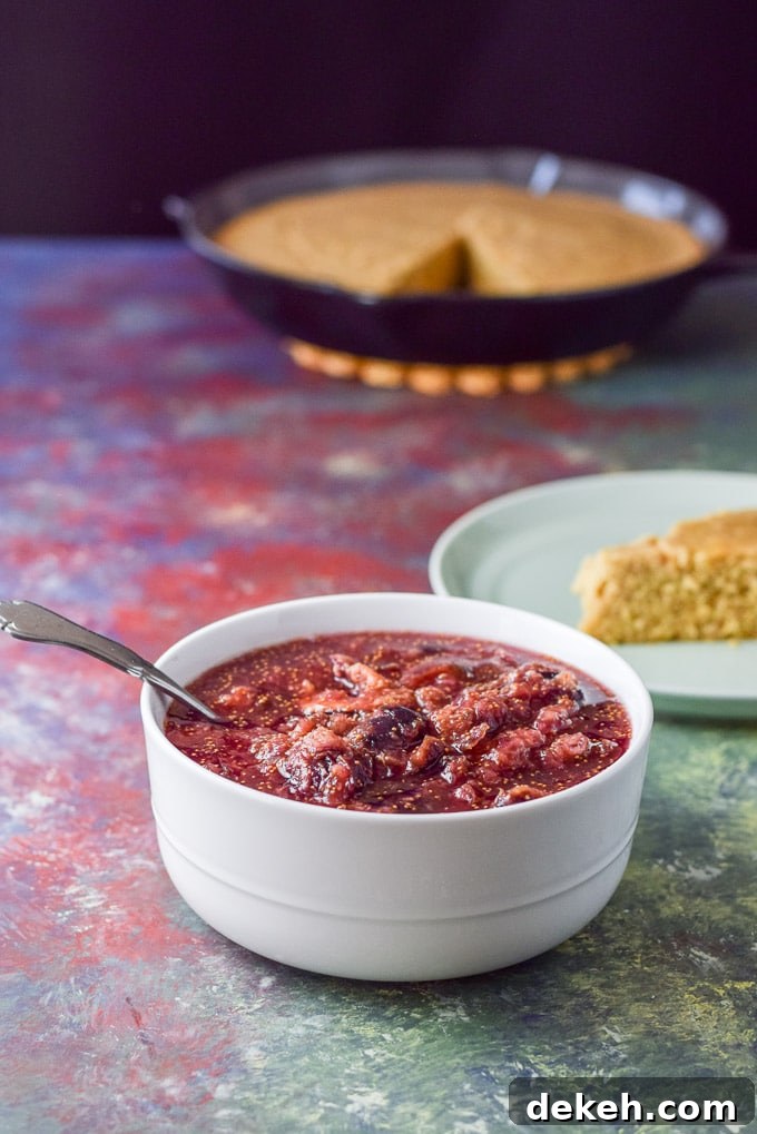 The sauce made of figs in a white bowl with some skillet of cornbread in the background