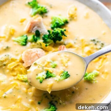 Spoon taking vegan broccoli cheddar soup from a bowl.