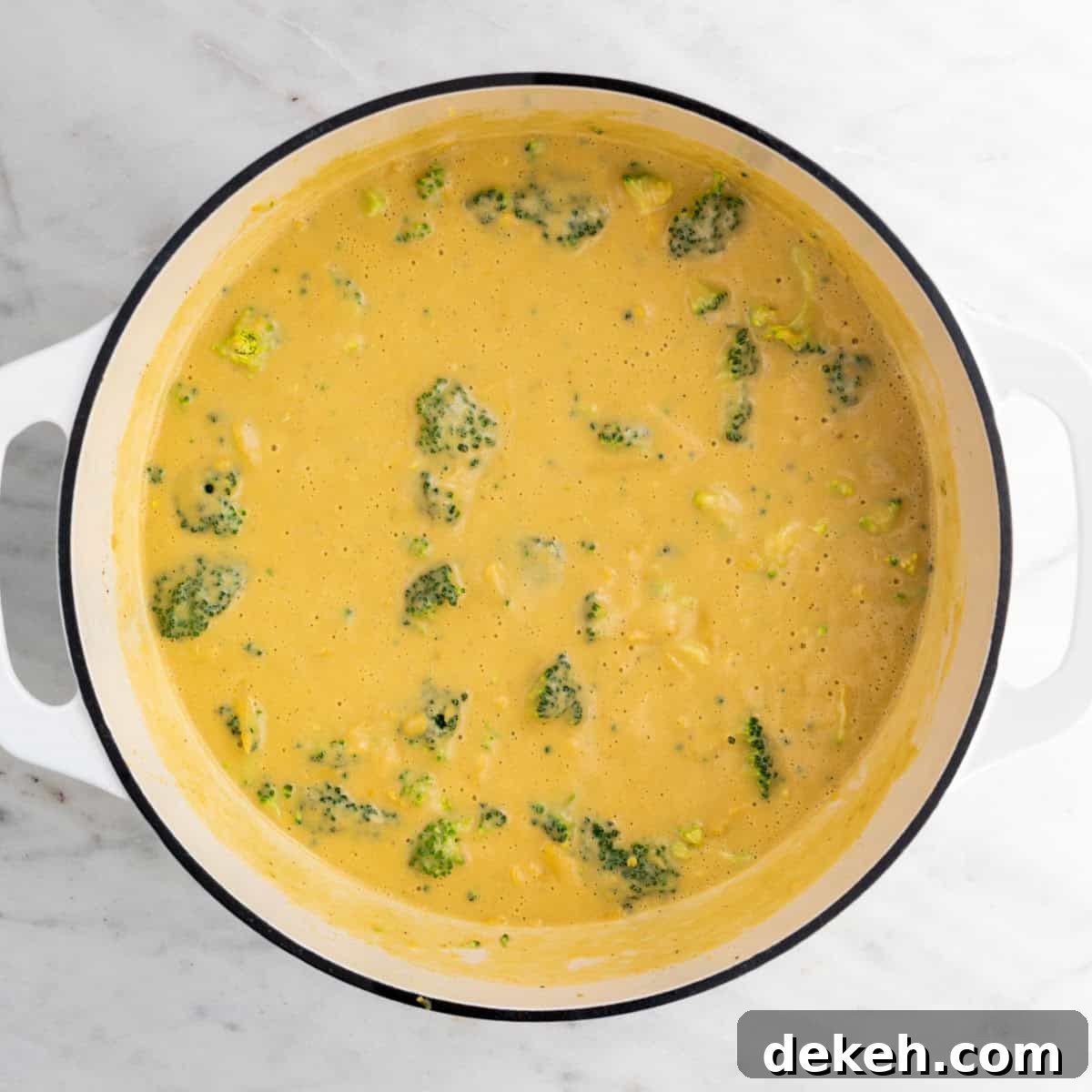 Blended soup in a large pot with broccoli and vegan cheese before cooking.