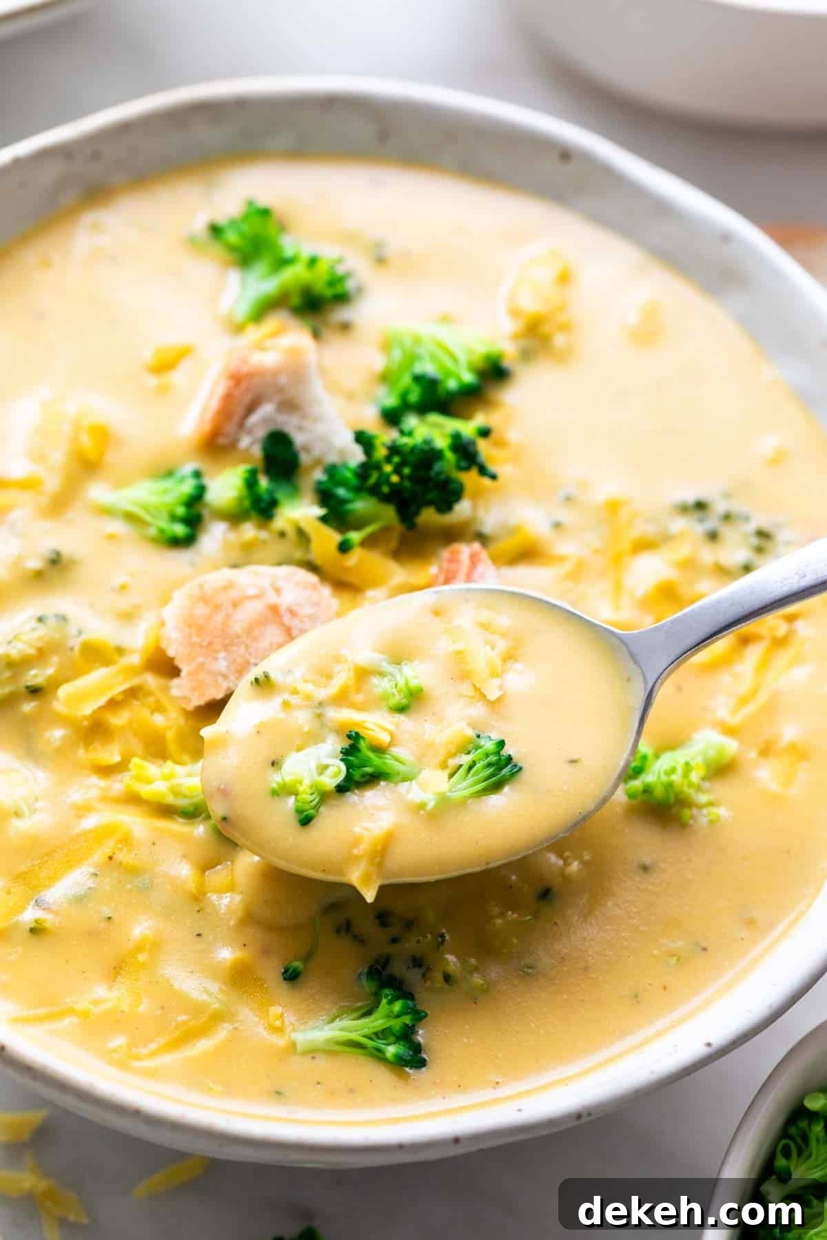 Spoon taking vegan broccoli cheddar soup from a bowl.
