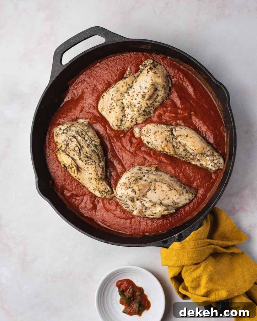 Chicken breasts added to tomato sauce.