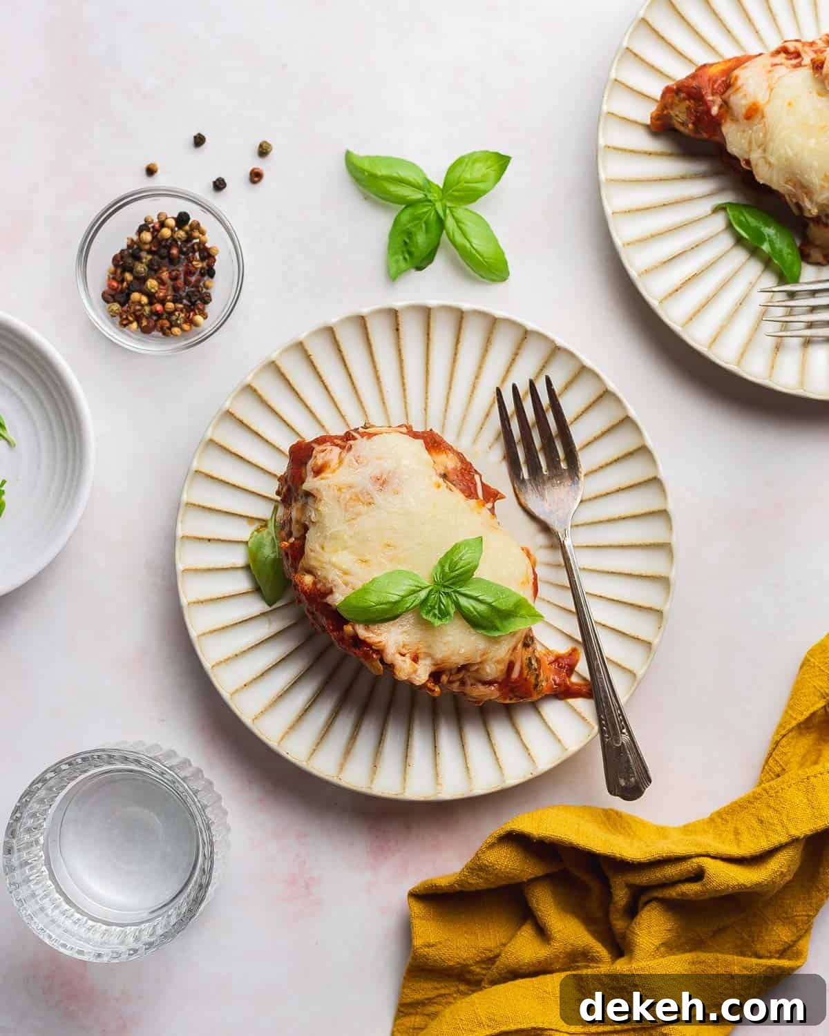 Overhead view of a scalloped plate with mozzarella chicken with a fork.