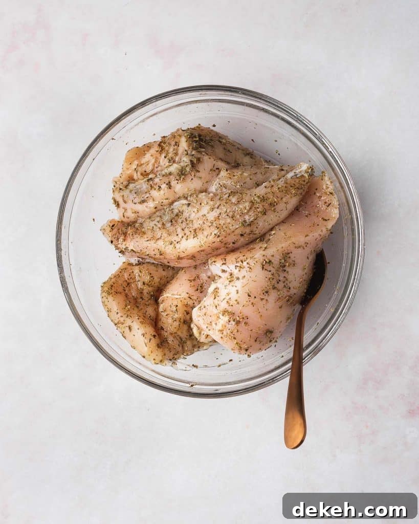 Chicken breasts seasoned in a bowl.