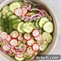 Cucumber radish salad in a serving bowl with red onion and sprigs of fresh dill.