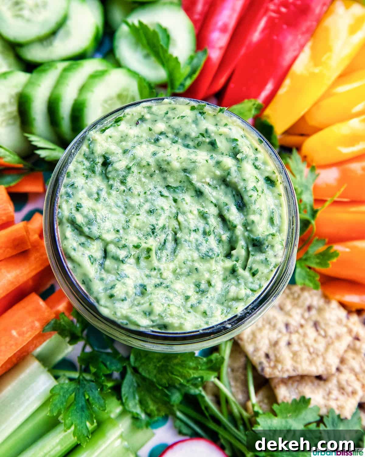 jar of vegan green goddess dressing in the center of sliced vegetables.
