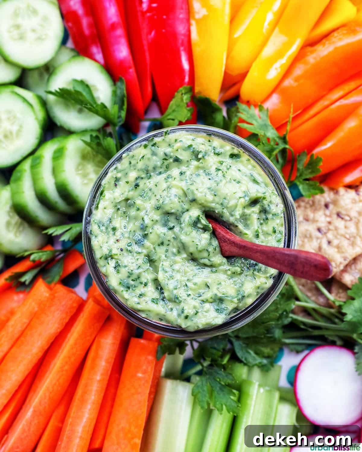 jar of vegan green goddess dressing in the center of sliced vegetables.