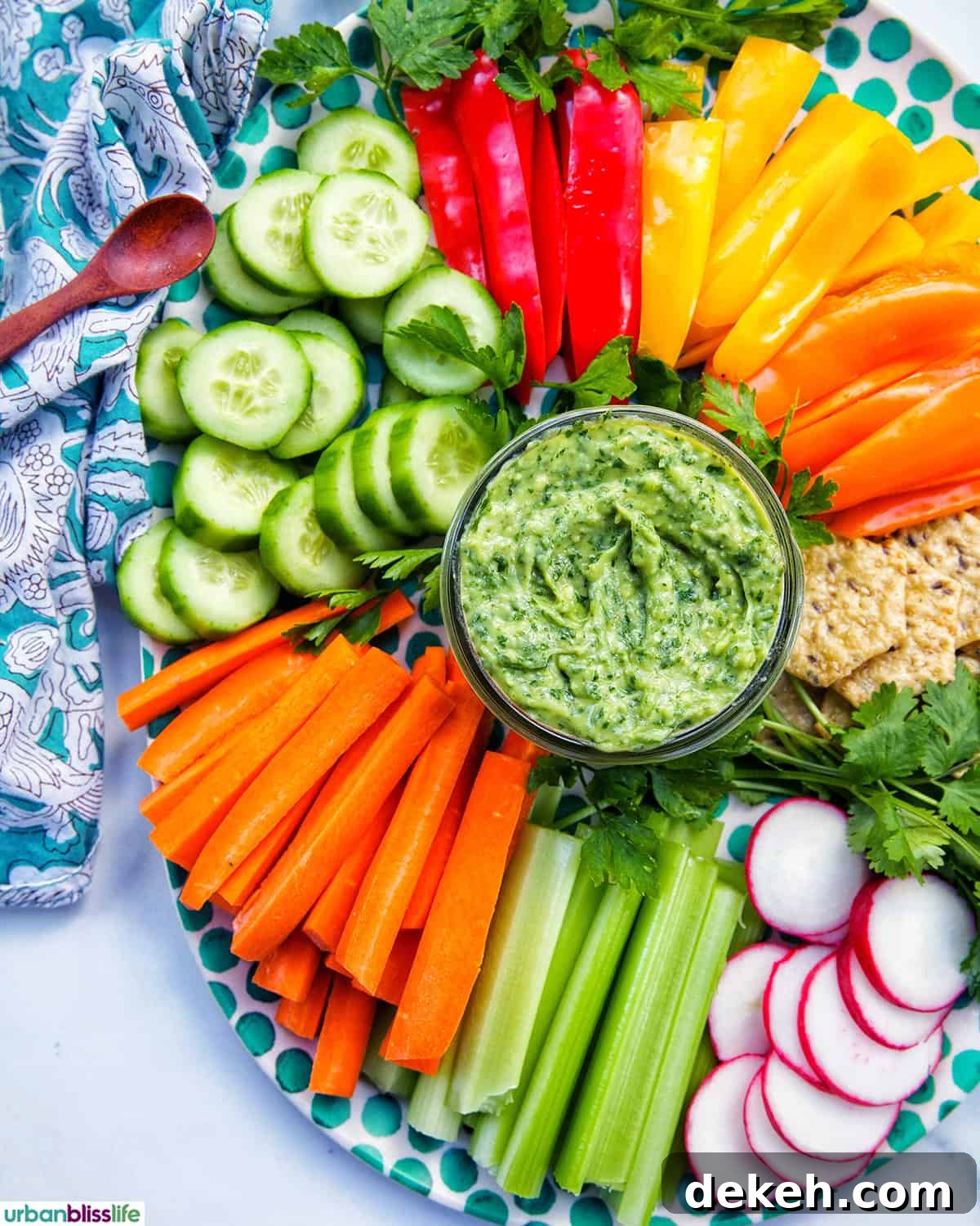 jar of vegan green goddess dressing in the center of sliced vegetables.