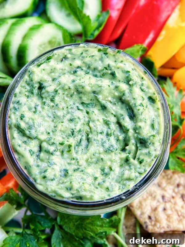 jar of vegan green goddess dressing in the center of sliced vegetables.