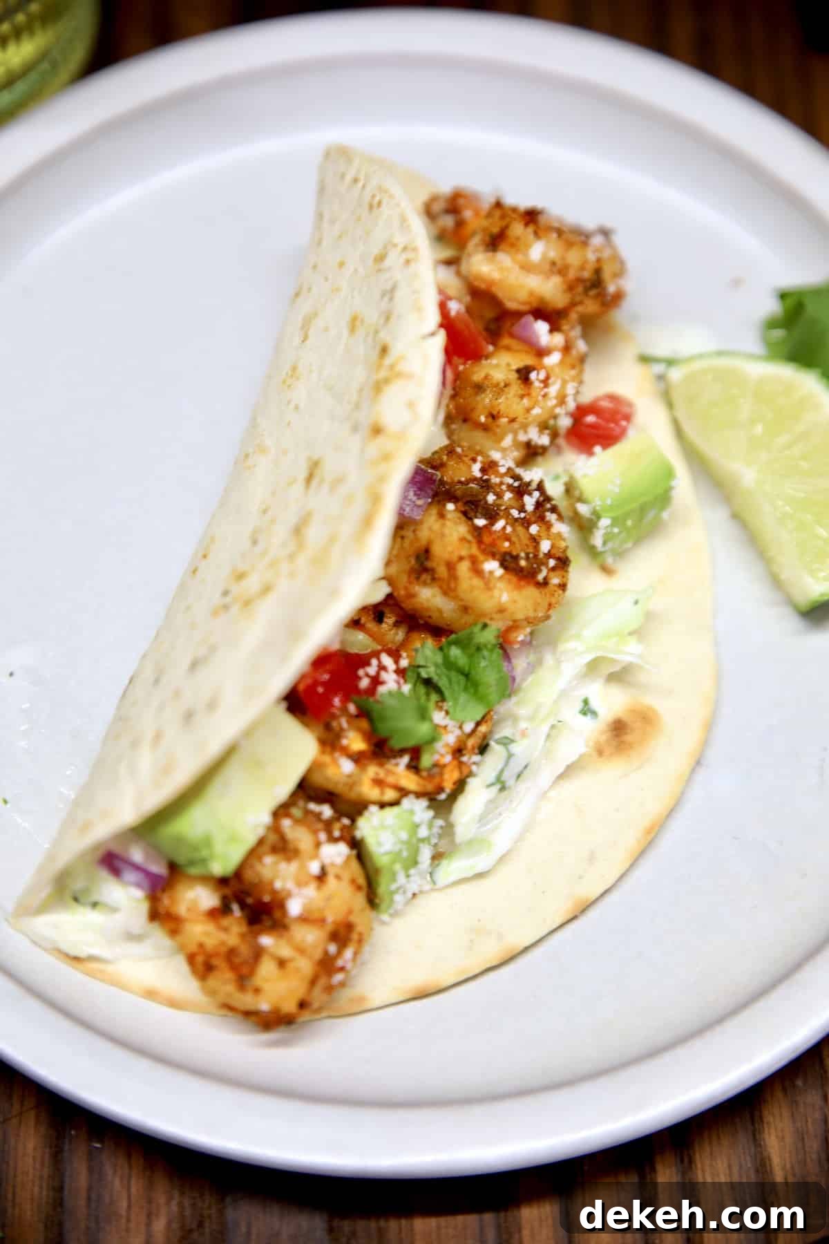 Closeup of shrimp taco on a plate with avocado and slaw.