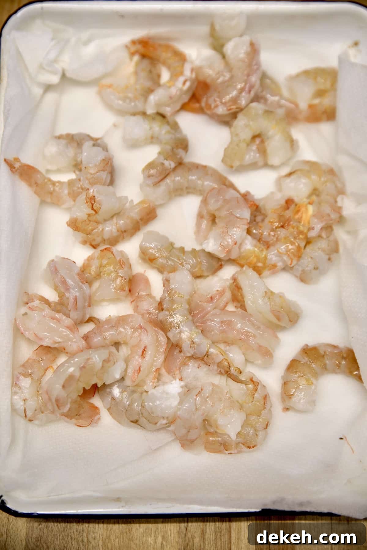 Drying shrimp on paper towel lined baking sheet.