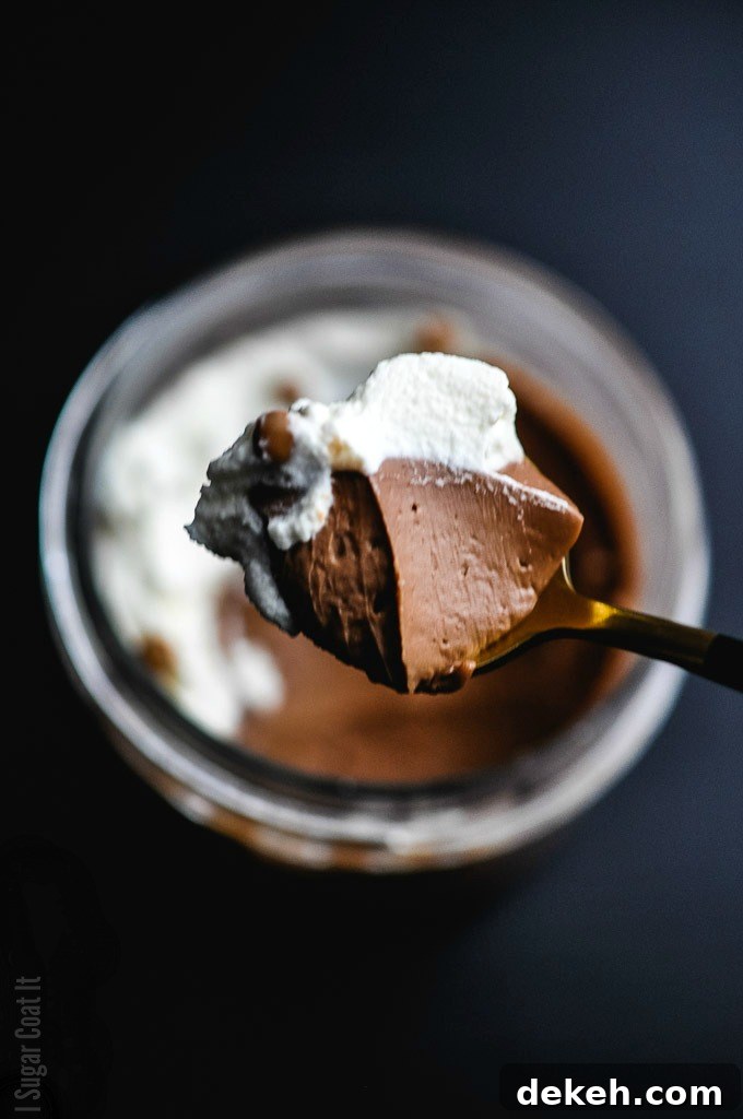 Spoonful of chocolate coffee pots de creme, topped with whipped cream and crisp pearls being scooped from a jar | I Sugar Coat It