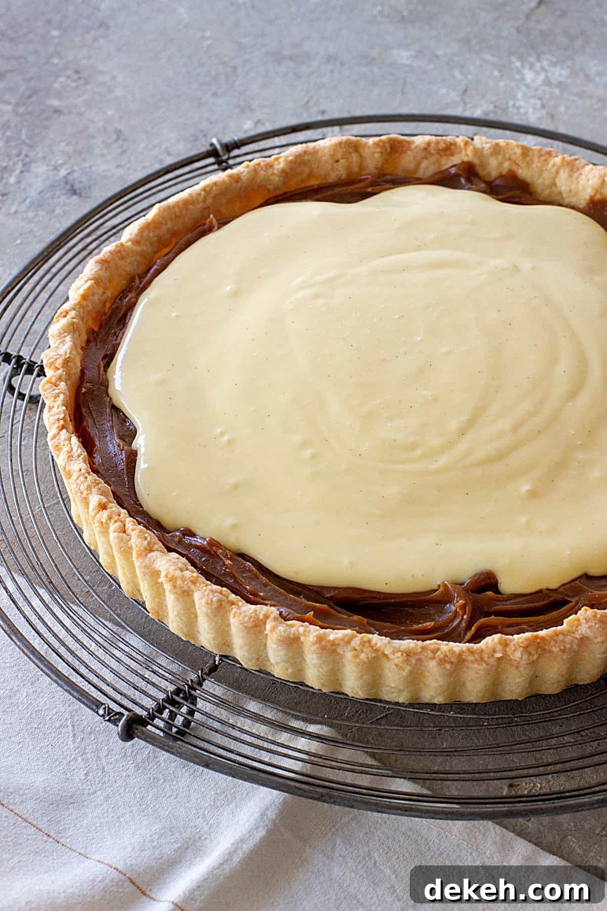 Coconut lemon tart with dulce de leche on a wire rack on a grey surface.