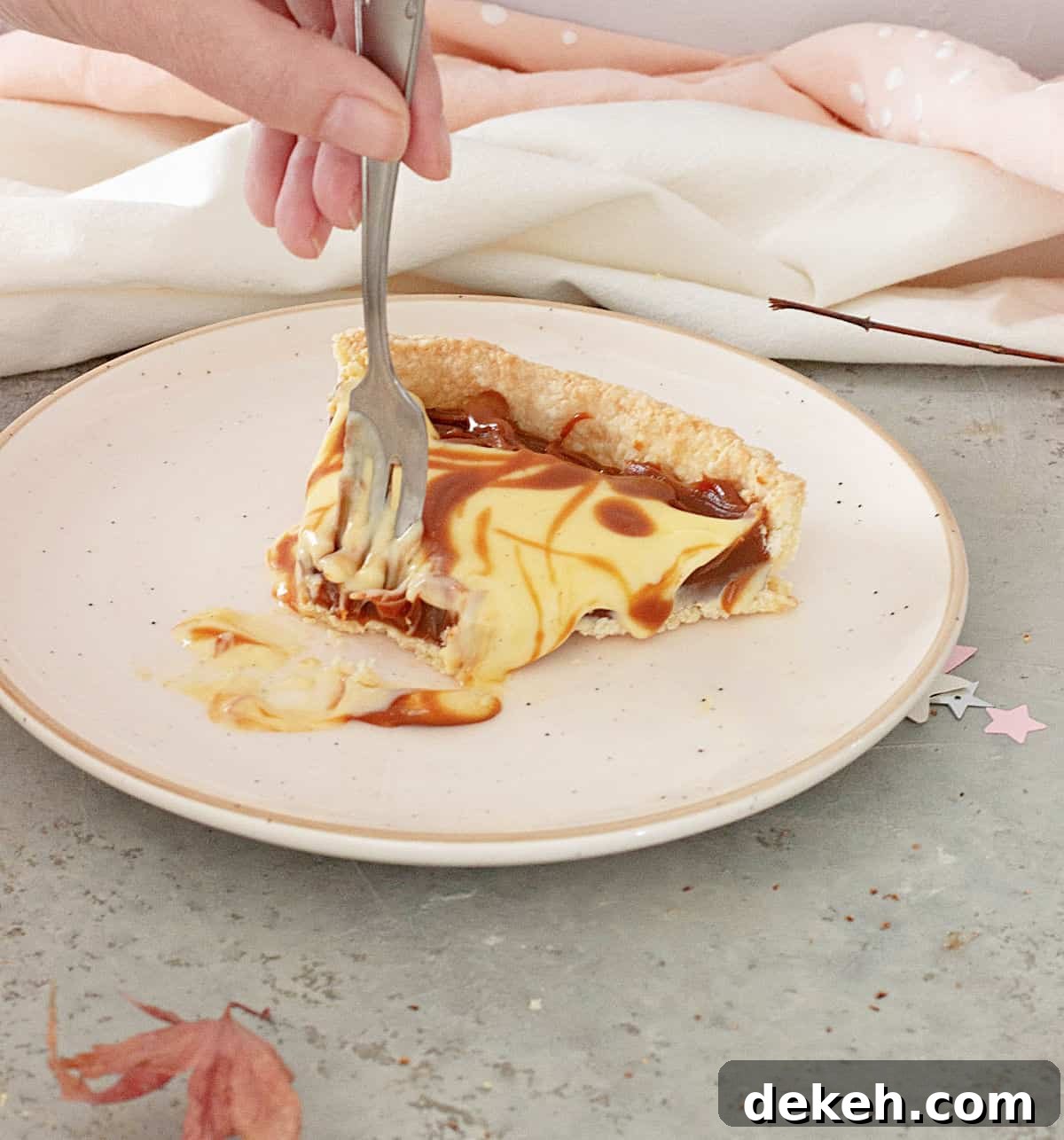 A forked slice of lemon dulce de leche tart on a pink plate on a grey surface.