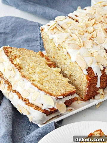 Close up of blue cloth with white tray of glazed coconut bread with almond topping.