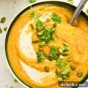 A bowl of pumpkin and sweet potato soup topped with chopped cilantro and pumpkin seeds.