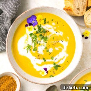 A bowl of paleo curried butternut squash soup garnished with flowers and fresh parsley.