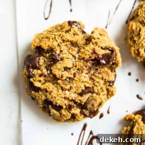 A paleo pumpkin chocolate chip cookie on a baking sheet with sea salt on top of it.