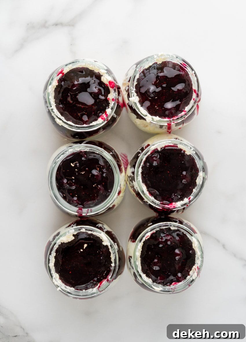 layers of cheesecake and blueberry filling in six small glass jars