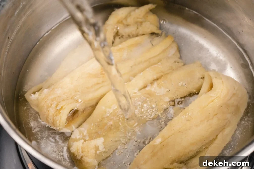 Saltfish in a saucepan with cold water being poured over the top