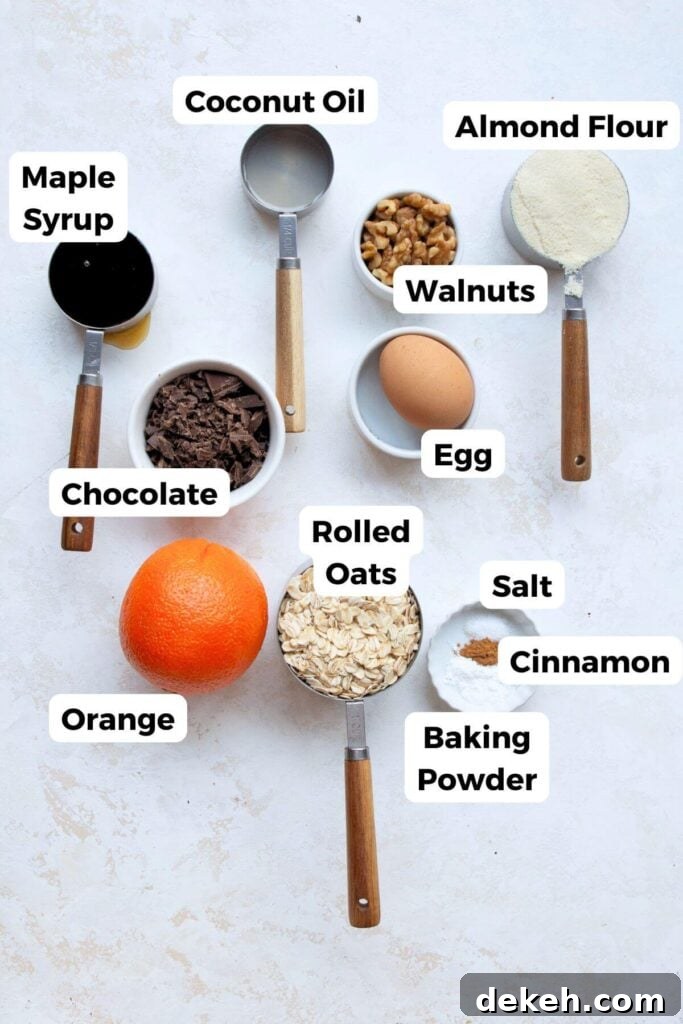 all ingredients in chocolate chip orange oatmeal cookies in bowls including rolled oats, egg, almond flour, walnuts, coconut oil, maple syrup, salt, cinnamon, baking powder, and orange zest
