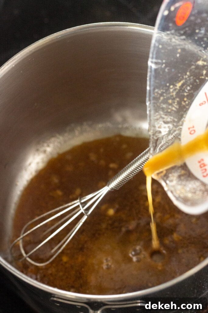 Pouring a brown marinade into a small saucepan with a whisk in it.