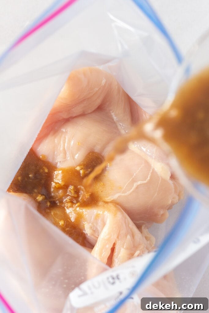 Pouring a brown marinade into a ziploc bag with raw chicken breasts in it.