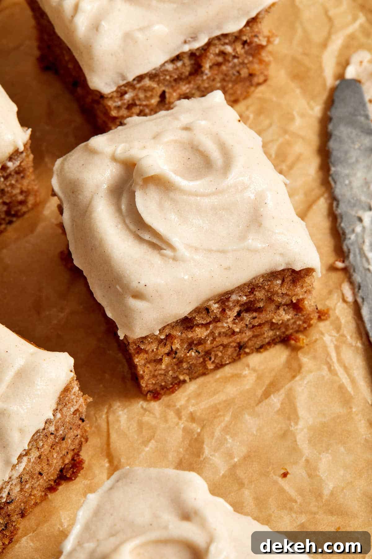 Angled view of cinnamon cream cheese frosting swirled on top of a piece of cake.