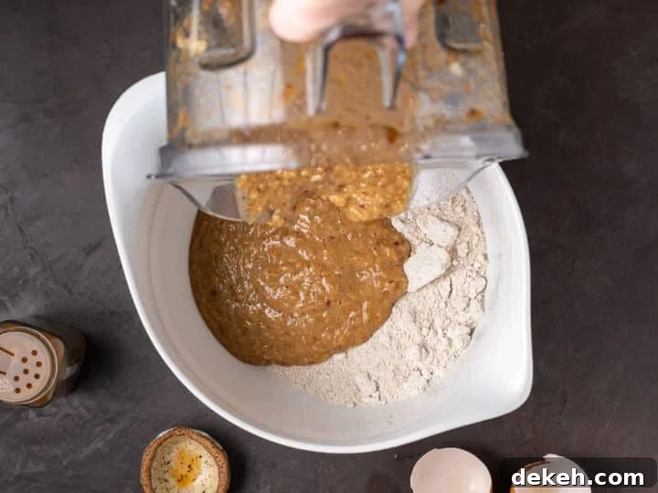 dumping wet ingredients in blender into the oat flour mixture in a bowl