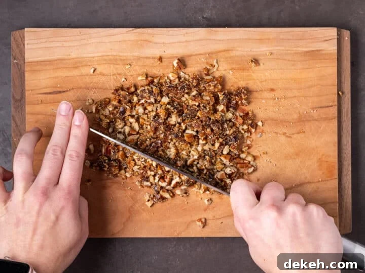 hands using a knife to chop together raw sugar, pecans and date