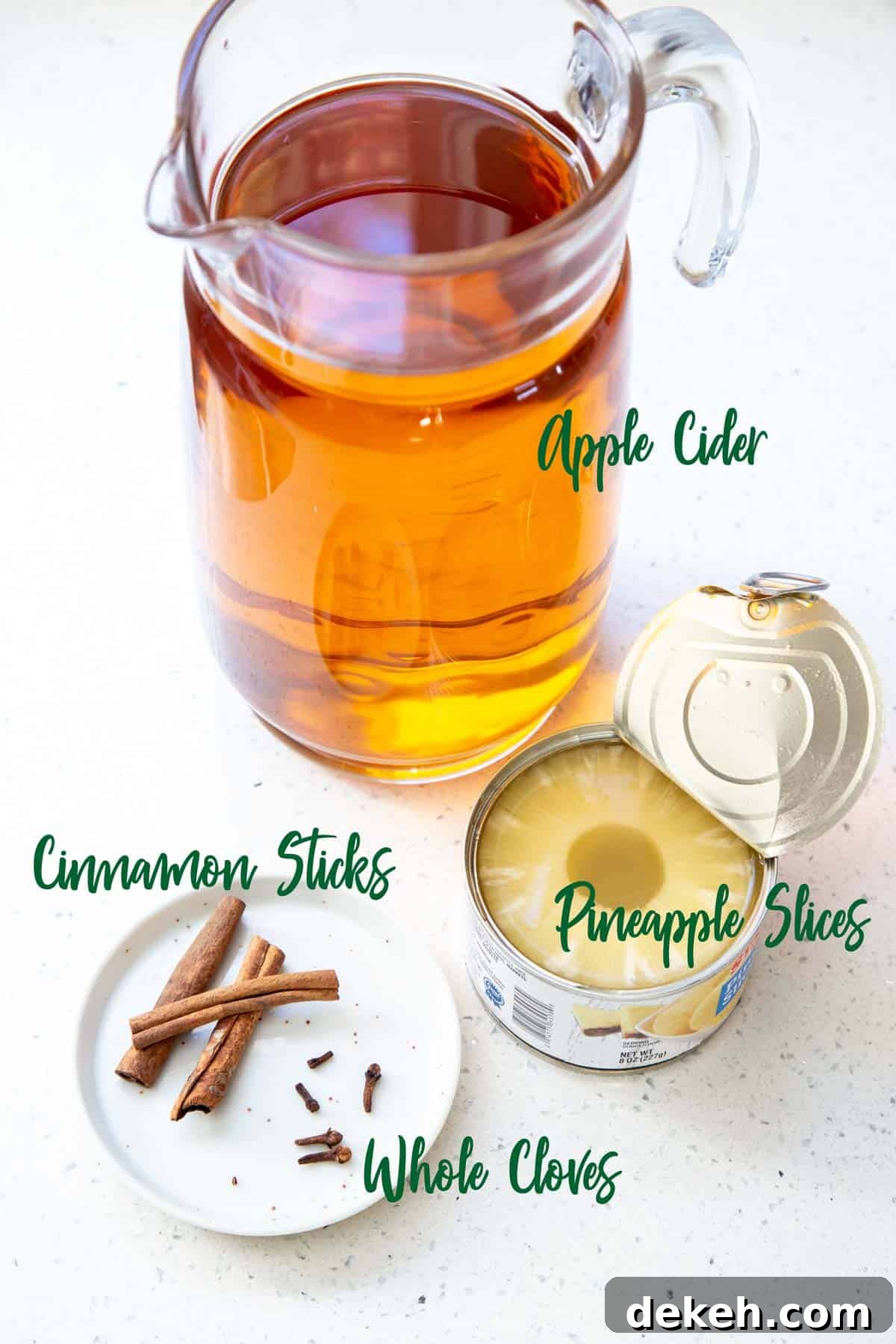 Ingredients for spiced apple cider on a white quartz countertop.