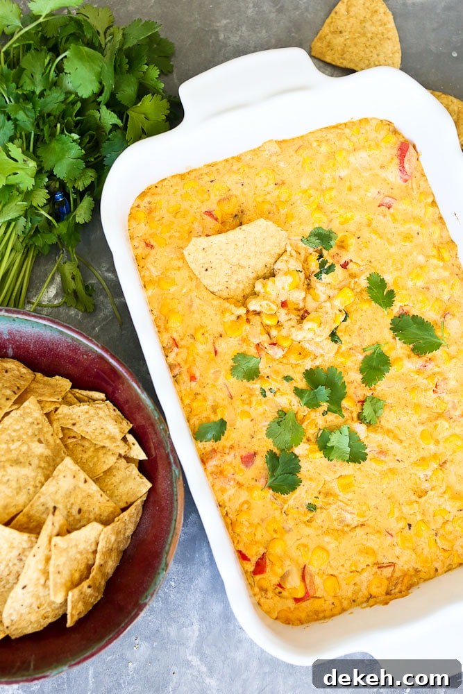 Hot Corn Dip Recipe next to a bowl of chips with a chip in the dip