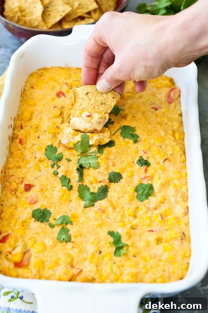 Hot Corn Dip Recipe the whole dish taking a scoop with a chip
