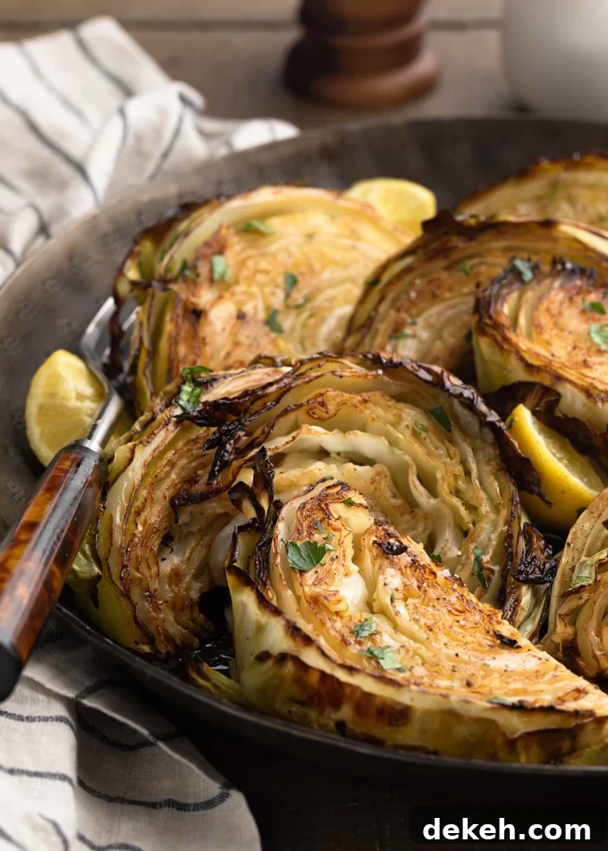 closeup of roasted cabbage wedges in a serving bowl with lemons and chopped parsley