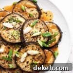 A top down view of a platter of roasted eggplant slices drizzled with miso sauce.
