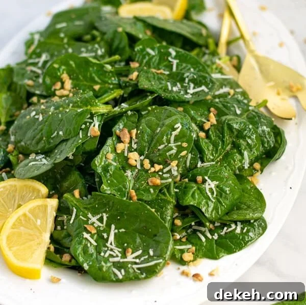 a white platter full of simple spinach salad with cheese and walnuts