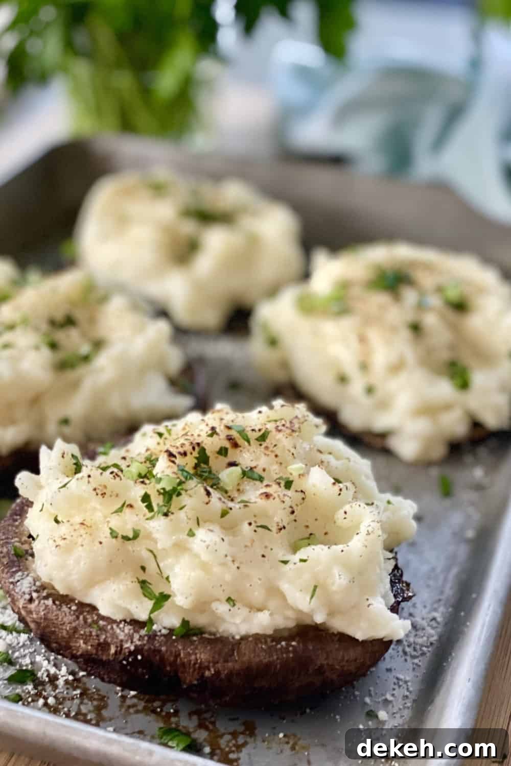 Large mashed potato stuffed mushrooms on a baking sheet.