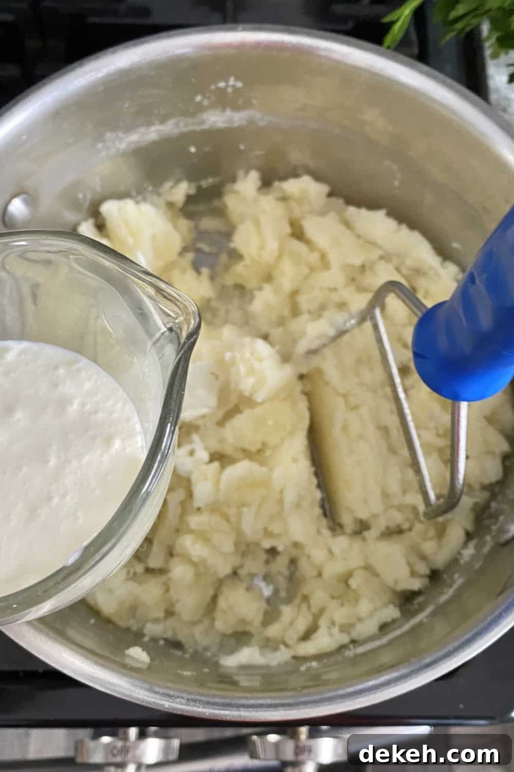 Adding heavy cream to partially mashed potatoes.