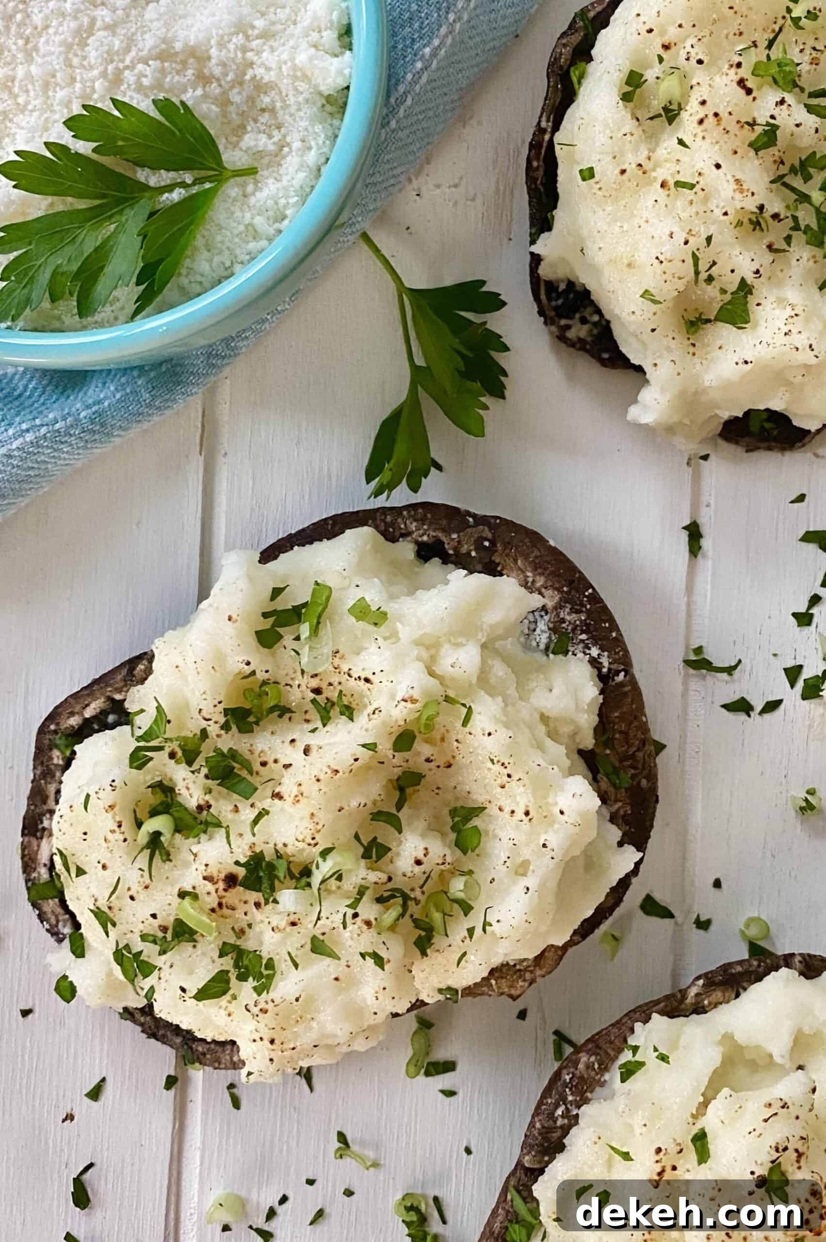 A bowl of grated parmesan cheese and 2 stuffed caps of mushrooms.