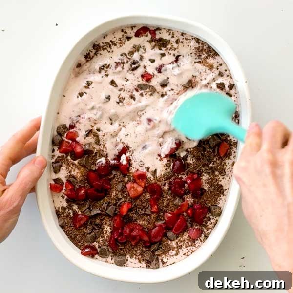 Stirring chocolate chunks and cherries into the ice cream.
